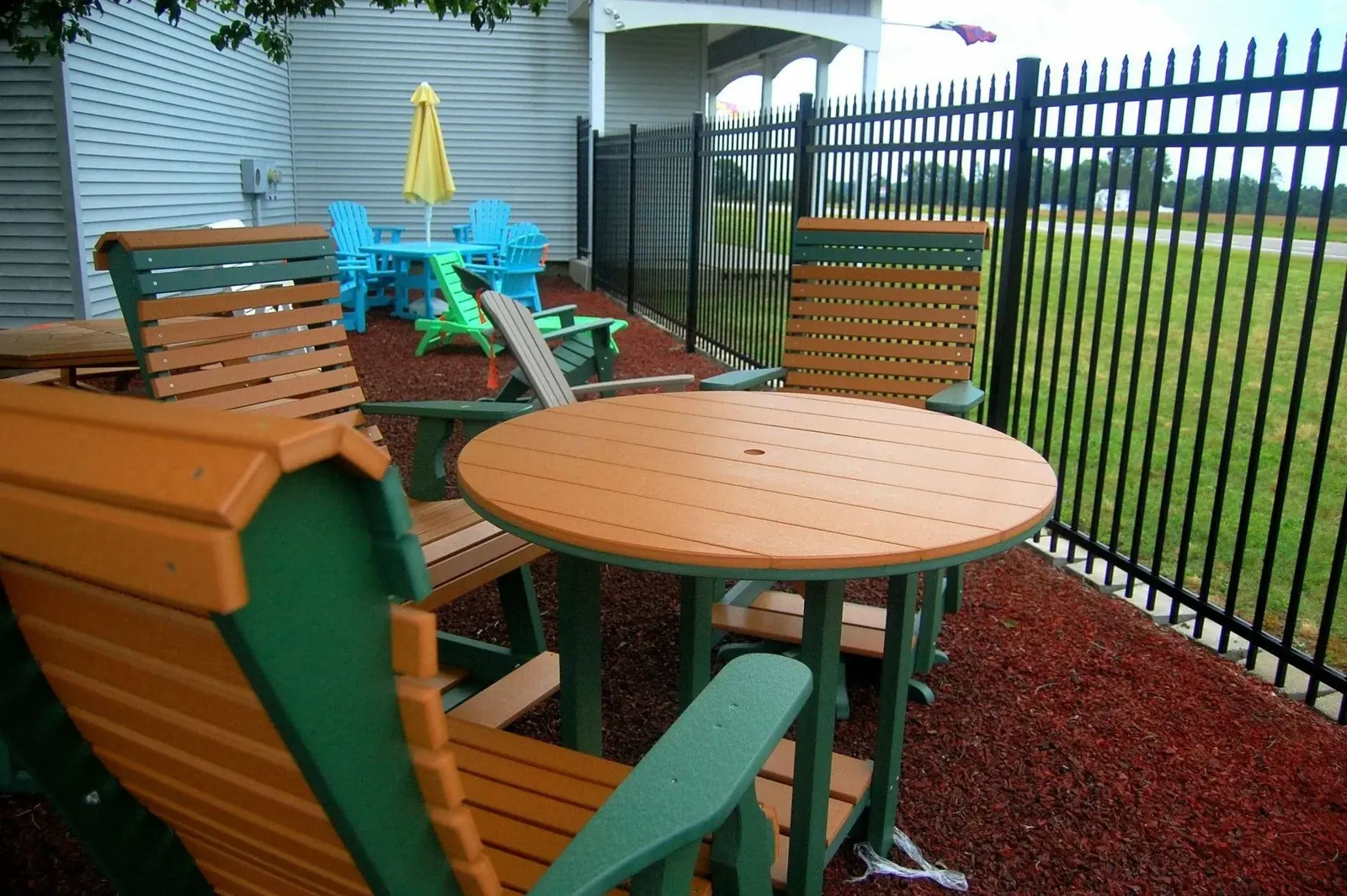 Orange and green poly Adirondack chairs around a round tan table