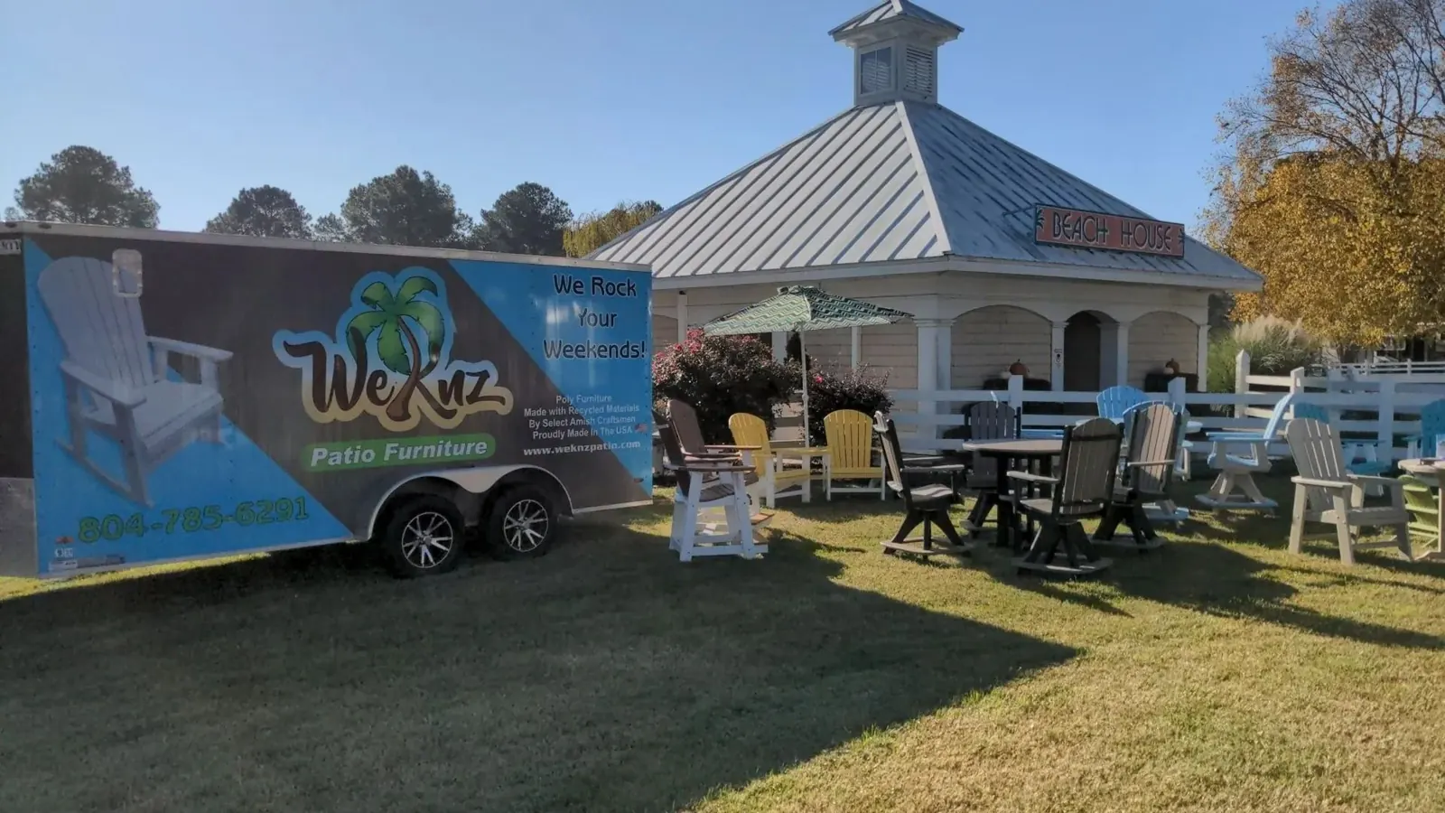 The Weknz showroom lot: the branded trailer, a white gazebo, and rows of poly dining sets on the lawn